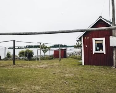 Red lakeside cabin with water view, rustic outdoor filming spot