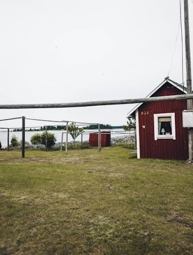 Red lakeside cabin with water view, rustic outdoor filming spot